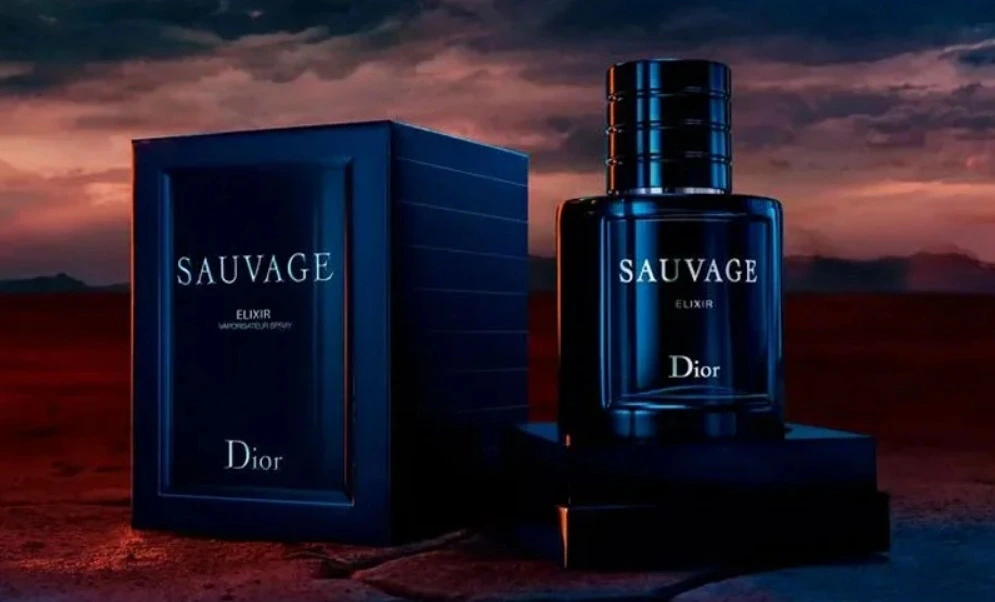 Frasco do perfume Sauvage Elixir da Dior ao lado de sua embalagem, em cenário escuro com fundo avermelhado ao entardecer, transmitindo intensidade, sofisticação e masculinidade marcante.