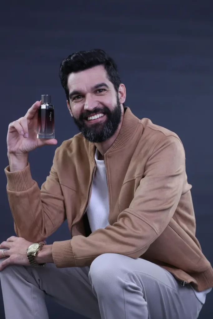 João da Barba segurando o perfume Malbec do Boticário – análise de cheiro e fixação